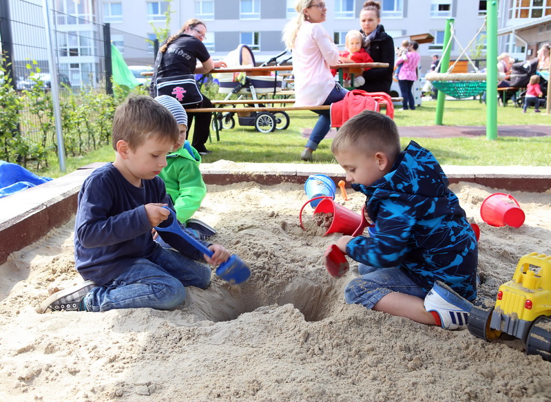 Drei Kleinkinder sitzen in einer Sandkiste und buddeln ein tiefes Loch